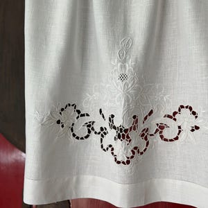 Puede incluir: Una taza de cerámica blanca con un asa negra y el texto "But First, Coffee" en negro, con una fuente de estilo manuscrito. La taza está sobre una superficie blanca.