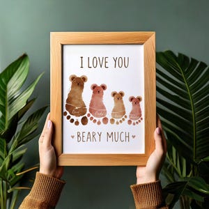 May include: A framed print with the words "I LOVE YOU" and "BEARY MUCH." The artwork features four bear figures made from footprints, each with a name. The frame is made of light-colored wood.