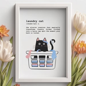 Peut inclure: Une impression encadrée blanche avec un chat noir assis dans un panier à linge. L'impression contient le texte "laundry cat" et une définition du terme.