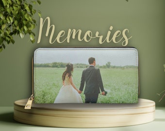 Puede incluir: Una cartera de cuero blanco con cremallera que muestra una foto de una pareja de recién casados en un campo. El texto "Memories" está impreso sobre la cartera.