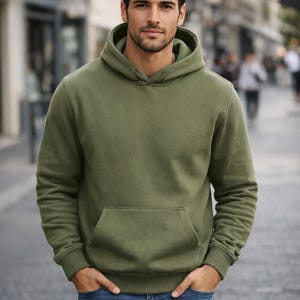 May include: Olive green hoodie with a kangaroo pocket and ribbed cuffs. The hooded sweatshirt is a casual garment, suitable for everyday wear. The long-sleeved top is made of a soft material.