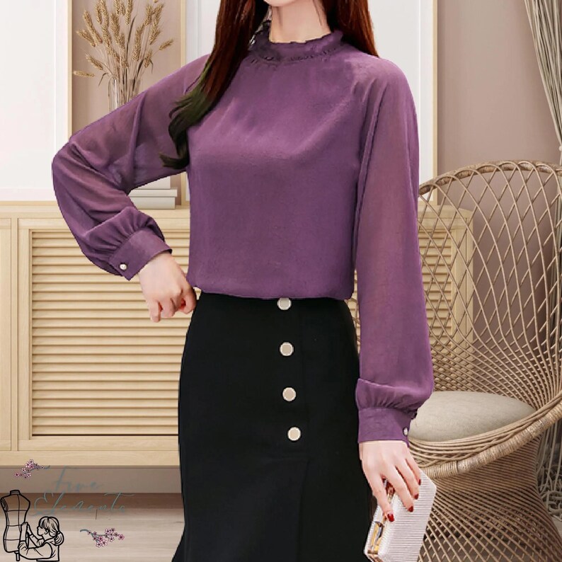 May include: A purple long-sleeve blouse with a ruffled neckline and buttoned cuffs. The blouse is paired with a black skirt featuring decorative buttons. The outfit is suitable for a professional or semi-formal setting.