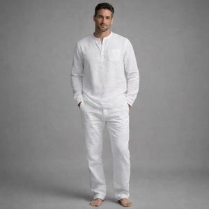 May include: A white linen shirt and pants set. The long-sleeved shirt has a mandarin collar and a single chest pocket. The pants are straight-legged. The outfit is made of a lightweight, breathable fabric.