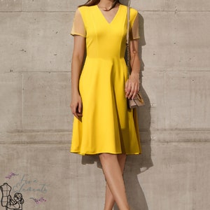 May include: A bright yellow dress with a v-neck and short sleeves. The dress has a fitted bodice and a flared skirt. The dress is made of a smooth, silky fabric.