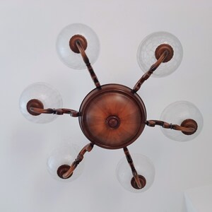 May include: A wooden chandelier with five frosted glass globes. The chandelier has a brown wooden base and arms.