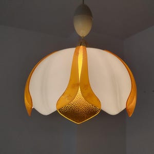 Peut inclure: Un luminaire suspendu vintage avec un abat-jour blanc en forme de tulipe et des accents dor&eacute;s. Le luminaire est suspendu &agrave; un support de plafond blanc. Les accents dor&eacute;s ont un aspect textur&eacute; et martel&eacute;.