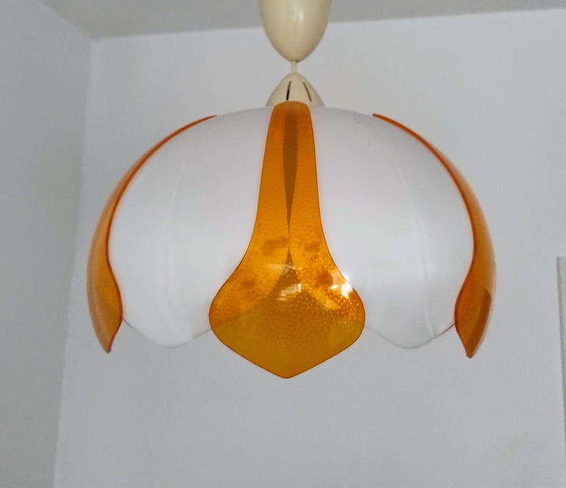 Peut inclure: Un plafonnier blanc et orange. La lampe a une forme arrondie en forme de tulipe avec des panneaux blancs et des accents orange. Les sections orange ont un aspect textur&eacute; et mouchet&eacute;.