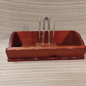 Könnte beinhalten: Ein Nussknacker-Set aus Holz mit rotbraunem Finish. Das Set enthält ein rechteckiges Tablett mit gewelltem Rand und drei Metallwerkzeuge: einen Nussknacker und zwei Picks. Das Tablett ist 30 cm lang.