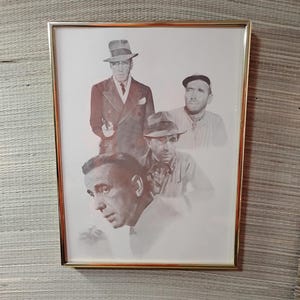 May include: A framed black and white print featuring four men in hats. The top figure is in a suit and tie, holding a gun. The other men are in casual attire. The frame is gold-colored.