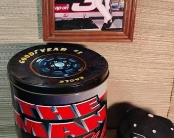 Colección de recuerdos de Dale Earnhardt con una imagen de una gorra de coche fundido a presión, una lata de boxes y una tarjeta de novato.