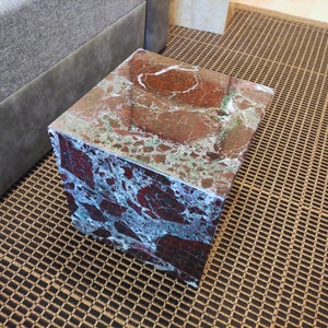 May include: A square, red, green, and white marble end table with a polished surface.