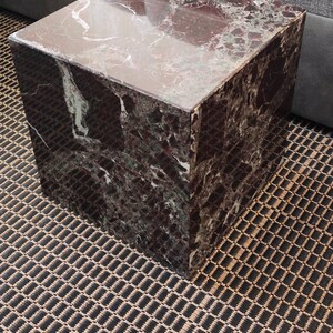 May include: A square, dark brown marble end table with a polished surface. The table has a unique pattern of white and green veins throughout the marble.