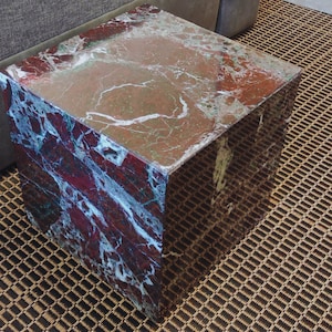 May include: A square, red and white marble end table with a smooth, polished surface.