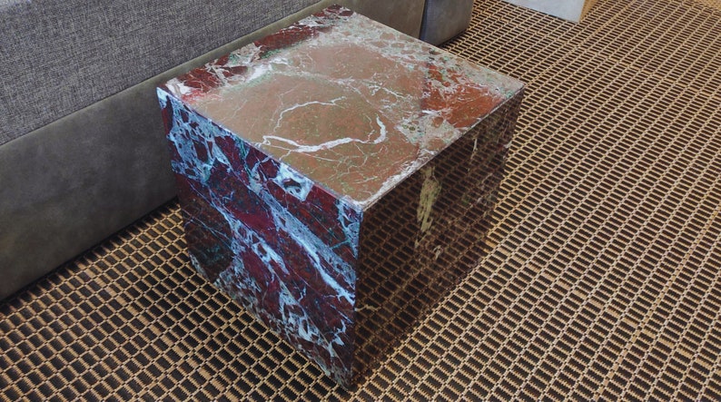 May include: A square, red and white marble end table with a smooth, polished surface.
