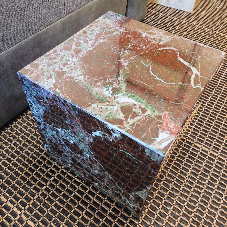 May include: A square, red and green marble end table with a polished surface.
