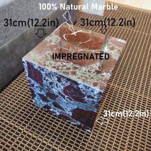 May include: A square, red, green, and white marble end table with the words "100% Natural Marble" and "IMPREGNATED" printed on the top. The table measures 12.2 inches on each side.