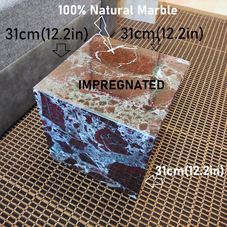 May include: A square, red, green, and white marble end table with the words "100% Natural Marble" and "IMPREGNATED" printed on the top. The table measures 12.2 inches on each side.