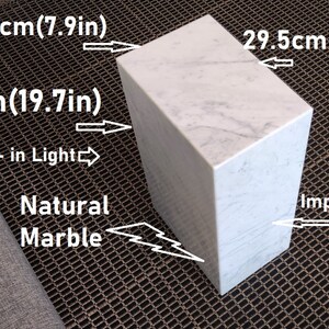 May include: A white marble cube with a built-in light. The cube measures 20 inches by 29.5 inches by 50 inches. The marble is natural and impregnated.