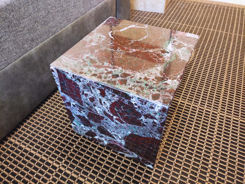 May include: A square, red and green marble end table with a polished surface.