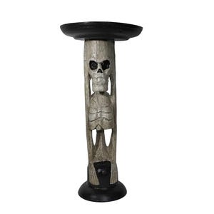 May include: A tall candle holder featuring a carved light gray skeleton figure as the central pillar. The base and the circular top platform are finished in a solid black color, providing a stark contrast to the textured, weathered gray bone appearance of the skeletal structure.