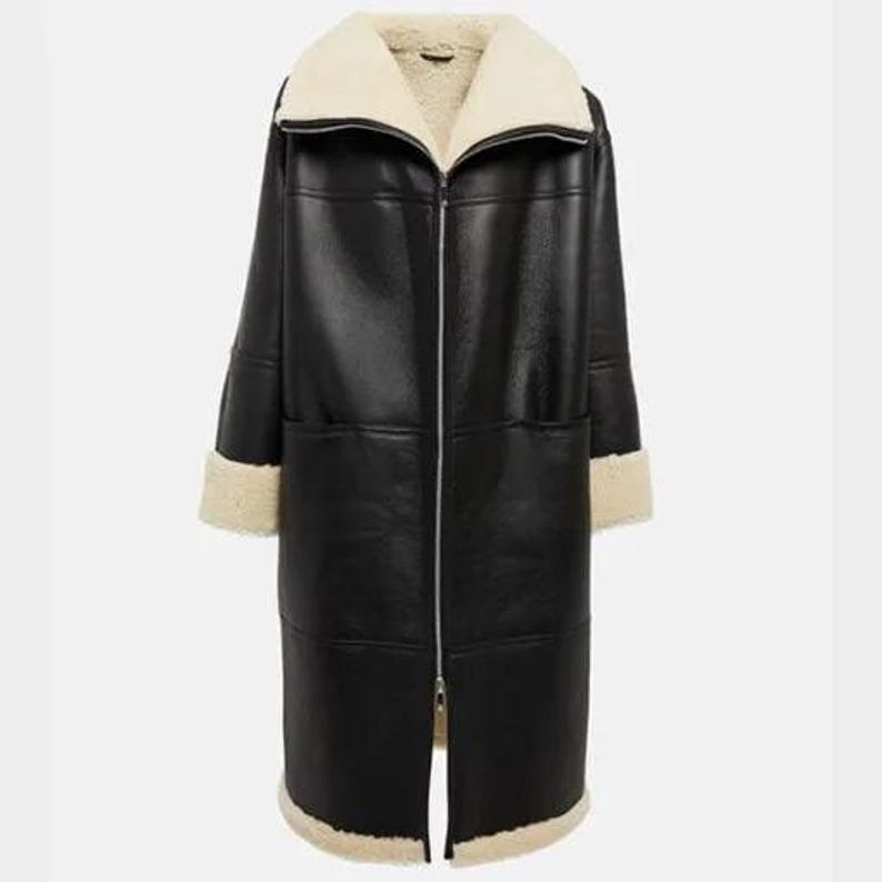 May include: A long black faux fur coat with a white shearling collar and cuffs. The coat has a zipper closure and two pockets.