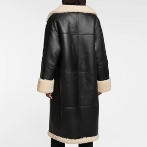 May include: A long black leather coat with a white shearling collar and cuffs. The coat has a zipper closure and a buttoned flap.