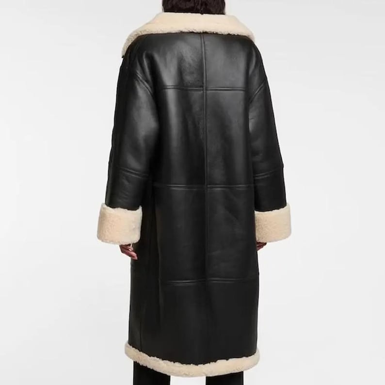 May include: A long black leather coat with a white shearling collar and cuffs. The coat has a zipper closure and a buttoned flap.