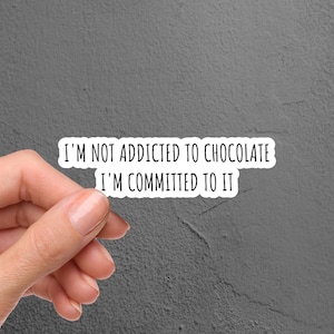May include: White sticker with black text that reads "I'm not addicted to chocolate I'm committed to it".