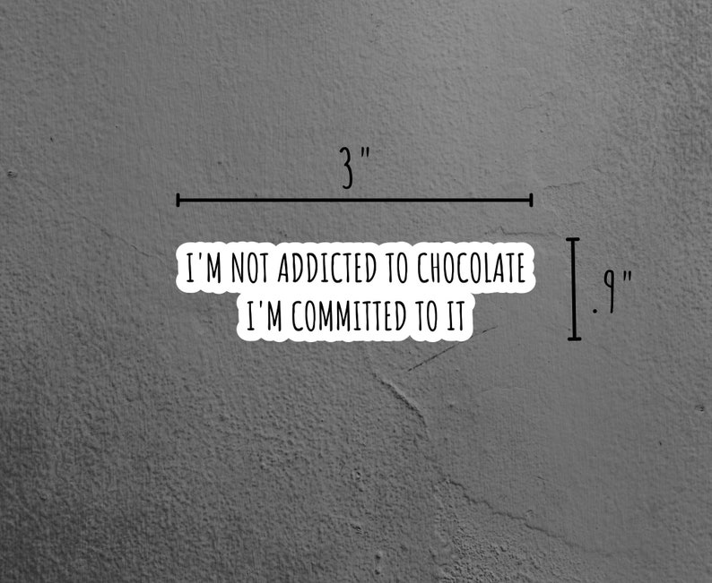 May include: A white sticker with black text that reads "I'm not addicted to chocolate I'm committed to it". The sticker is on a gray textured surface. The sticker is 3 inches wide and 9 inches tall.