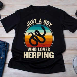 May include: Black t-shirt with a retro-style graphic of a snake and the text "Just a boy who loves herping".