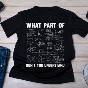 Puede incluir: Camiseta negra con texto blanco que dice "Qué parte de" seguido de una serie de ecuaciones matemáticas y luego "No entiendes".
