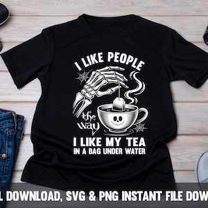 May include: Black t-shirt with a white graphic of a skeleton hand holding a tea bag over a teacup with a smiling face. Text reads "I LIKE PEOPLE the way I LIKE MY TEA IN A BAG UNDER WATER."