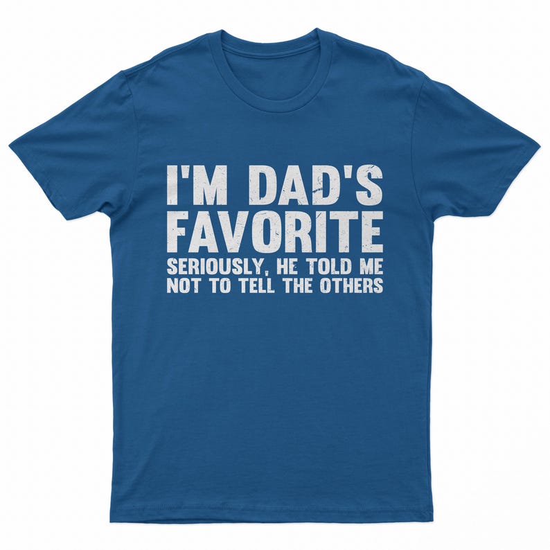 May include: A blue t-shirt with the text "I'M DAD'S FAVORITE" in large white letters. Below, smaller text reads "SERIOUSLY, HE TOLD ME NOT TO TELL THE OTHERS". The shirt is a casual wear item.