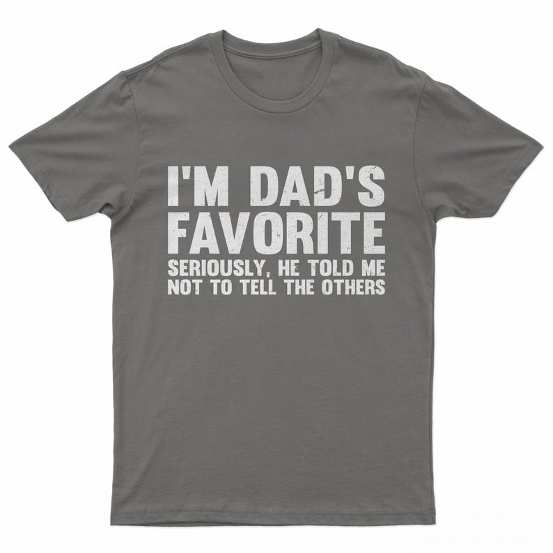May include: A gray t-shirt with the text "I'M DAD'S FAVORITE" in large white letters. Below, smaller text reads "SERIOUSLY, HE TOLD ME NOT TO TELL THE OTHERS."