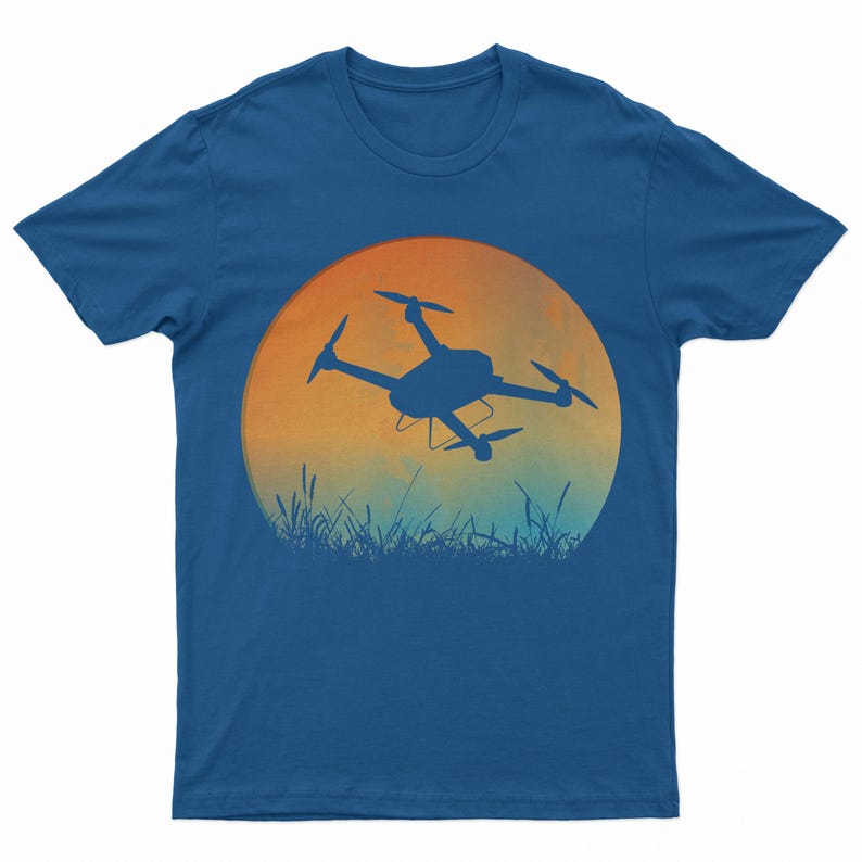 May include: A blue t-shirt with a graphic of a drone flying in front of a sunset. The drone is a silhouette against the orange and blue sky.