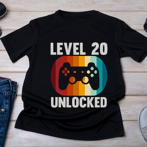 May include: Black t-shirt with a retro-style video game controller graphic and the text "LEVEL 20 UNLOCKED".