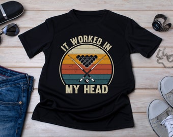 May include: Black t-shirt featuring a vintage-style graphic of a pool table with cues and balls. The text "It worked in my head" is printed below the graphic.