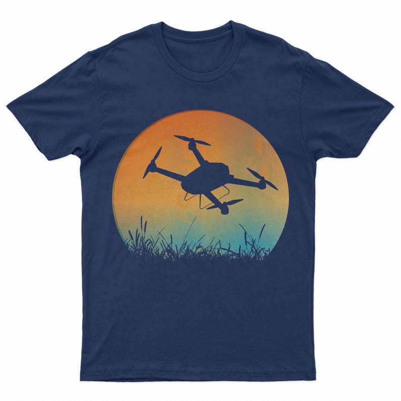 May include: A navy blue t-shirt with a silhouette of a drone flying in front of a sunset. The sunset is a gradient of orange, yellow, and blue.