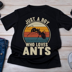 以下が含まれることがあります： アリのヴィンテージスタイルのグラフィックと「Just a boy who loves ants」というテキストがプリントされた黒いTシャツです。