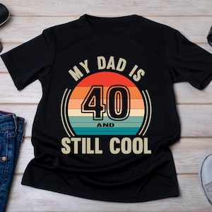 May include: Black t-shirt with a vintage-style graphic that says "My Dad is 40 and Still Cool".