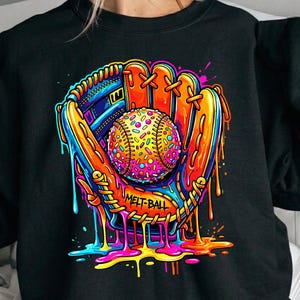 May include: Black sweatshirt featuring a colorful graphic of a baseball in a mitt. The baseball is covered in sprinkles, and the mitt has a vibrant, dripping paint effect. The text "MELT-BALL" is visible on the mitt.