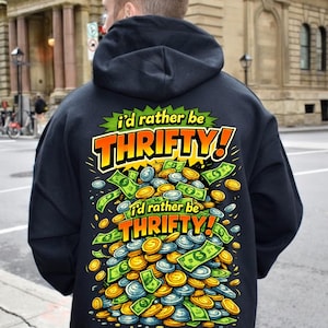 Puede incluir: Sudadera con capucha negra con el texto "I'd rather be THRIFTY!" en naranja y amarillo, con un gráfico de dinero y monedas. El diseño está en la parte posterior de la sudadera.
