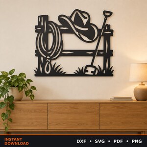 Peut inclure: Une décoration murale en métal noir représentant un thème western avec un chapeau de cowboy posé sur une clôture en bois, un lasso enroulé suspendu sur le côté et une pelle appuyée contre les lattes de la clôture sur un mur clair.