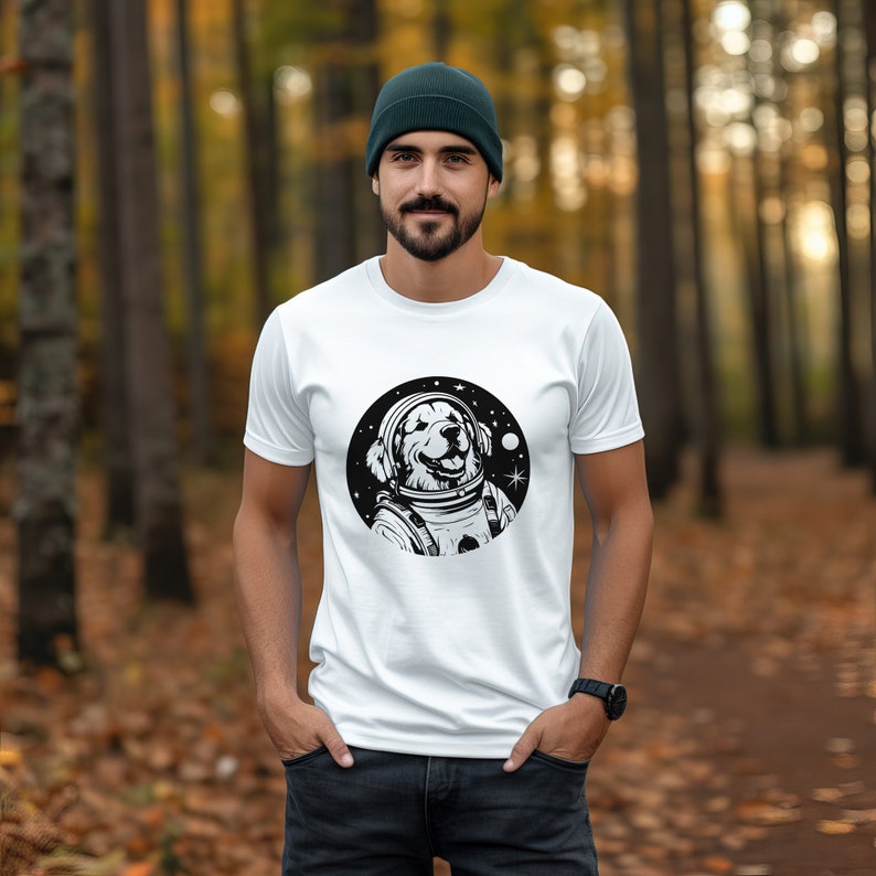 Puede incluir: Camiseta blanca con un gr&aacute;fico en blanco y negro de un golden retriever con un casco de astronauta. El perro sonr&iacute;e y tiene estrellas a su alrededor.