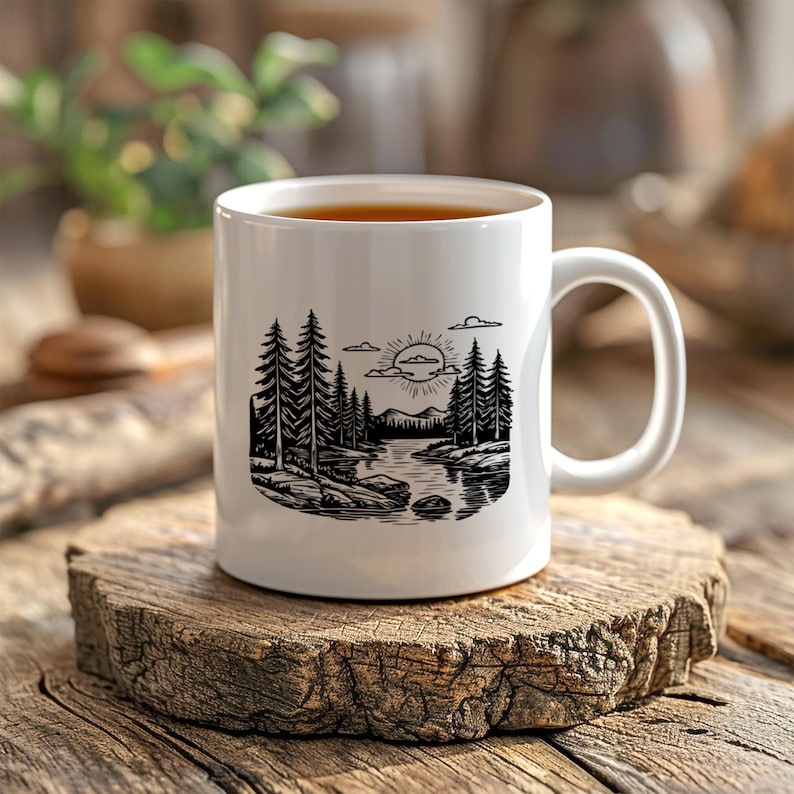 May include: A white ceramic mug with a black and white nature scene illustration. The design features a river, trees, mountains, and a sun. The mug is filled with a dark liquid and sits on a wooden surface.