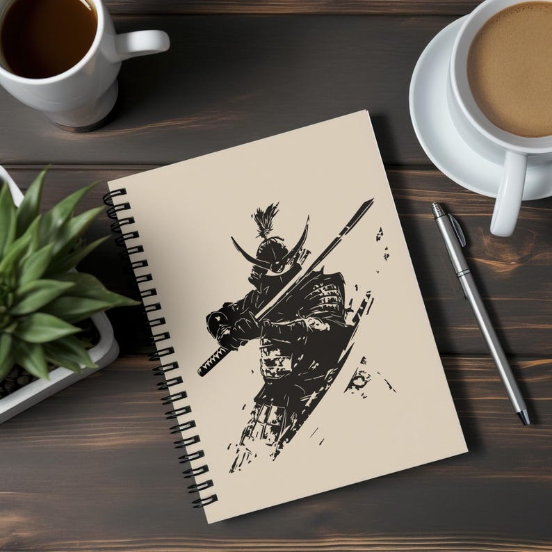 K&ouml;nnte beinhalten: Spiralgebundenes Notizbuch mit einer Schwarz-Wei&szlig;-Illustration eines Samurai-Kriegers in voller R&uuml;stung, der ein Katana h&auml;lt. Das Kunstwerk befindet sich vor einem beigefarbenen Hintergrund. Das Notizbuch liegt auf einer Holzoberfl&auml;che, mit Kaffeetassen und einem Stift in der N&auml;he.