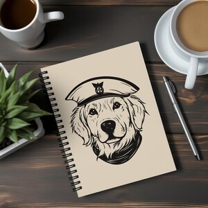 Puede incluir: Una libreta de espiral con una cubierta beige que presenta una ilustraci&oacute;n en blanco y negro de un golden retriever con un gorro de marinero. El perro est&aacute; mirando directamente al espectador.