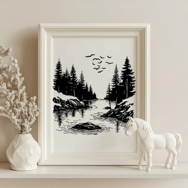 May include: Black and white framed art print depicting a serene forest scene with a river, trees, and birds in flight. A white ceramic horse figurine and a white vase with dried flowers are on a shelf in front of the print.