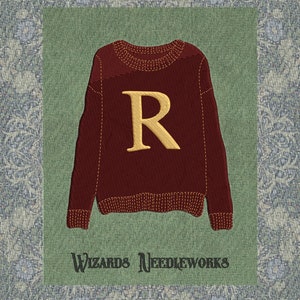Könnte beinhalten: Gestickter weinroter Pullover mit goldenem "R" auf grünem Hintergrund, vor einem gemusterten blau-weißen Stoff. Der Text "Wizards Needleworks" steht unter dem Pullover.