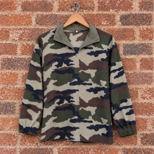 Könnte beinhalten: Ein langärmeliger Pullover mit Camouflage-Muster in Olivgrün, Dunkelbraun, Schwarz und Beige. Das Kleidungsstück verfügt über einen Viertel-Reißverschluss mit einem einfarbigen olivgrünen Kragen sowie elastische Bündchen an den Ärmelenden.